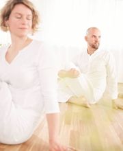 Ruhige Gruppenaufnahme im hellen Yogastudio mit mehreren Teilnehmenden in einer sitzenden Drehhaltung. Das Bild vermittelt Achtsamkeit, Körperwahrnehmung und eine entspannte Kursatmosphäre.