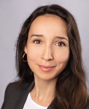 Portrait einer Mitarbeiterin mit braunen Haaren und Augen, die sympathisch in die Kamera schaut.