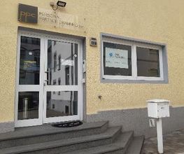 Außenansicht des Gebäudes mit Eingangsbereich. Gelbe Fassade und WBS TRAINING Schild im Fenster. Weißer Briefkasten.