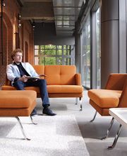 Ein stilvoll eingerichteter Loungebereich mit modernen Sitzmöbeln in warmen Farbtönen. Die harmonische Kombination aus industriellen Elementen, großzügigen Glasflächen und gemütlichen Polstermöbeln schafft eine entspannte Atmosphäre für Meetings, kreative Pausen und informelle Gespräche.