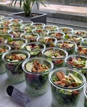 dean&david Catering | Pforzheim - Chicken Teriyaki Bowls im Glas mit Reis, Salat, Gurke, Limette und Frühlingszwiebeln auf einem hellen Buffet für Firmenveranstaltungen.