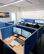 Arbeitsplätze mit 2 PC-Bildschirmen Tastatur und Maus, blauen Bürostühlen und blauen Trennwänden.