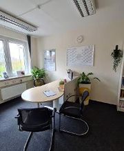 Ein Büro mit Schreibtisch und Regal.