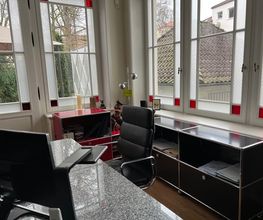 Büro von A. Hampel mit großem Arbeitsplatz direkt an den hellen Fensterflächen.