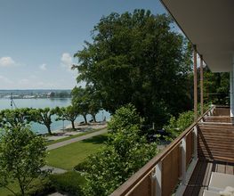 DAS HAUS AM SEE. Genießen Sie den direkten Seeblick von Ihrem privaten Balkon aus. Erleben Sie, wie das Haus mit dem See lebt und der stete Blick auf das Wasser den Rhythmus Ihres Aufenthalts bestimmt.