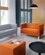 Eine stilvolle Lounge-Ecke mit modernen Sitzmöbeln und durchdachtem Design. Die Kombination aus kräftigen Farben, hochwertiger Verarbeitung und einer offenen Raumgestaltung schafft eine einladende Atmosphäre für produktive Meetings und entspannte Pausen.