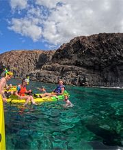 4 personas haciendo tour de kayak en el mar con cueva de fondo