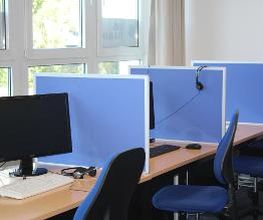mehrere PC-Arbeitsplätze mit Trennwänden.