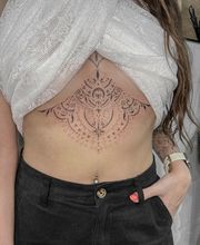 Fineline Underboob Tattoo. Ornamental Design. Schön unterhalb der Brust angebracht, bis hoch zum Sternum.