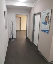 Bild vom Flur im Innenbereich. Zu sehen ist ein Garderobenständer, mehre Türen zu Räumen sowie ein Werbeplakat an der Wand.