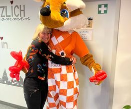Eine Frau umarmt das Fuchsmaskottchen der WBS SCHULEN.