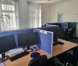 Mehrere Arbeitsplätze mit jeweils 2 Bildschirmen, einem Bürostuhl, Tastatur und Maus. 