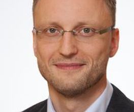 Portrait eines Mitarbeiters mit Brille. 