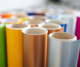 mediaService Bremen | Full-Stack Werbeagentur - Eine farbenfrohe Auswahl an aufgereihten Folienrollen in verschiedenen Farben wie Gelb, Grün, Orange und Magenta für die professionelle Fahrzeugbeschilderung und Werbetechnik.