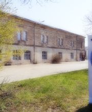 Zweistöckiges Gebäude aus Backsteinen. Davor steht ein Werbeaufsteller der WBS TRAINING.