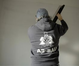 Mitarbeiter von AS-Bau beim Innenausbau, auf dem Rücken das Firmenlogo.