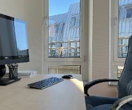 Beratungsplatz mit Blick aus dem Fenster. Auf dem Schreibtisch befindet sich ein PC-Bildschirm, eine kabellose Tastatur und Maus sowie Notizblöcke und Stiftebecher.
