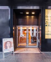 Außenansicht vom Eingang zum modernen Schulungsgebäude. Schwarze Marmorfassade. Vor der Tür steht ein Plakataufsteller von WBS TRAINING. 