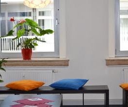 Gemütliche Sitzbank mit Kissen am Fenster. Schöne Zimmerpflanzen im Hintergrund.