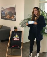 Eine Frau steht neben einem Strandstuhl und hält eine Eintrittskarte in der Hand. Gewinnspiel für Umschüler "Eishockeykarten"