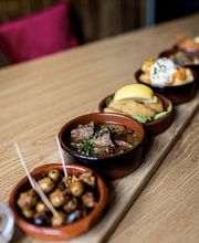 Auswahl kleiner Tapas-Schälchen auf dem Holztisch der Tapas Bar Léon. "Oma's Brett".