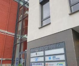 Außenansicht eines mehrstöckigen Gebäudes. An der Wand ist ein Branchenkompass zu sehen.
