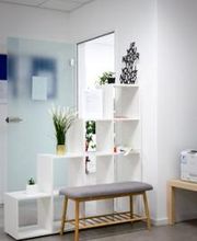 Druckerplatz  mit einem weißen Regal auf dem eine Pflanze und Deko steht. Davor steh eine kleine Sitzbank.