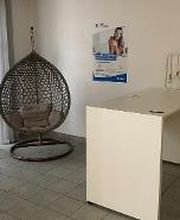 Eingangsbereich mit Hängesessel und einer Theke. Links ein Beistelltisch mit Zimmerpflanze. An der Wand ein Plakat der WBS TRAINING.