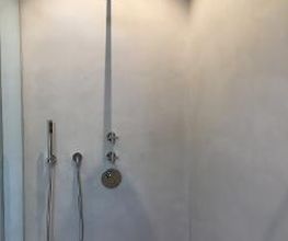 Minimalistische Dusche: Fugenlose Wandgestaltung in der Dusche mit Unterputz-Armaturen und eleganter Regendusche.
