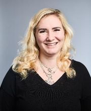 Portrait einer blonden Mitarbeiterin, die fröhlich in die Kamera lächelt.