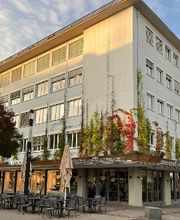 Ansicht eines Bürogebäudes, im Erdgeschoss befindet sich ein Restaurant.