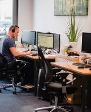 Ein Mann mit Headset sitzt an einem PC-Arbeitsplatz.