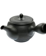 Diese Japanische Einhand-Teekanne (Kyusu) aus dem Töpferort Tokoname, ist von einer kunstvoll eingearbeiteten Oberflächenstruktur gekennzeichnet. Ringförmig legt sich die leicht geriffelte Struktur um den Korpus des Kyusu. Nur der Fuss, der obere Rand und der Griff des Deckels sind unstrukturiert. Als Abgrenzung fungiert eine fein gepunktete Linie. Der dunkle Ton zeigt sich in einem warmen, dezenten Schwarz. Ein Qualitätsprodukt aus Japan.

Diese Kyusu eignet sich perfekt für die Zubereitung von japanischen Grüntees. Der Tee kann sich in der Teekanne frei bewegen und seine Aromen hervorragend an das Teewasser abgeben. Die Teekanne eignet sich für Grüntee-Kenner und auch für Tee-Einsteiger. Durch die relativ kompakte Größe ist diese Kyusu ein idealer Reisebegleiter, damit man seinen Lieblingstee auch auf Reisen zubereiten kann.

✓ JAPANISCHE TEEKANNE MIT INTEGRIERTEM TEESIEB - Dank eines integrierten Teesiebs, werden die Teeblätter beim Einschenken in eine Teetasse in der Teekanne zurück gehalten. Das Tonsieb ist sehr fein gearbeitet, so dass sich die Kanne vorzüglich für die Zubereitung edler Tees wie etwa Kabuse Sencha Shinryoku oder Gyokuro eignet.

✓ TEEKANNE FÜLLMENGE CA. 350 ml - Diese Kyusu hat ein Fassungsvermögen von ca. 350 ml. Daher eignet sich die Kyusu sehr gut für die Zubereitung kleinerer Teemengen und der Tee kann mehrfach aufgegossen und dadurch effizienter ausgenutzt werden.

✓ MULTI-AUFGUSS-FÄHIG - Grüner Tee kann in der Regel mehrfach aufgegossen werden und diese Kyusu eignet sich hervorragend für Mehrfachaufgüsse. Für die Grüntee-Zubereitung ca. 1-2 TL Tee in die Kyusu geben und mit 60-75°C warmen Wasser aufgießen und ca. 40-60 Sekunden ziehen lassen. Die exakte Zubereitung von grünem Tee hängt von der Sorte und Qualität des Grüntees ab.