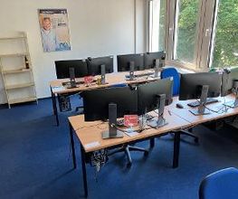 mehrere PC-Arbeitsplätze mit Monitoren, Tastatur, Maus und Headset.