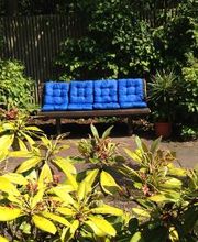 Eine Bank mit blauen Kissen in einem Garten.