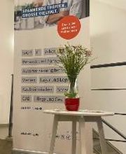 Roll Up WBS Training. Davor steht ein kleiner weißer Tisch mit einem Blumenstrauß.