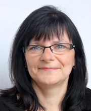 Portrait einer Bildungsreferentin mit schwarzen Haaren und Brille. Die Dame lächelt freundlich in die Kamera.