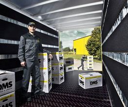 Mitarbeiter zwischen gestapelten DMS-Umzugskartons im Lkw