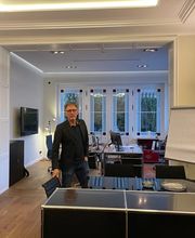 A. Hampel in den Büroräumen der PAKT Gruppe mit Blick auf den offenen Arbeits- und Besprechungsbereich.