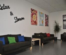 Pausenraum mit 3 Sofas und bunten Kissen. An der Wand mehrere farbenfrohe Bilder und ein Wandtattoo "Relax & Dream"