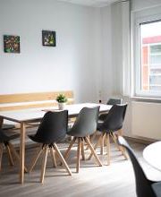 Ein Aufenthaltsraum mit mehreren Tischen und Stühlen.