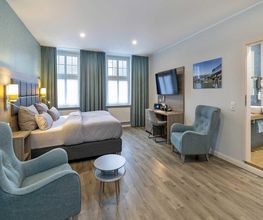 30 m² Komfort Doppelzimmer Nr. 12 im Haupthaus (1. Etage): Maximaler Schlafkomfort im 1,80 x 2,10 m Überlängen-Bett mit Komfortmatratze und XL-Decken. Inklusive 55″-Smart-TV, Qi-Ladestation, Laptopsafe sowie Bad mit XL-Tüchern und viel Ablagefläche