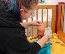 Schüler:in wäscht eine Babypuppe.