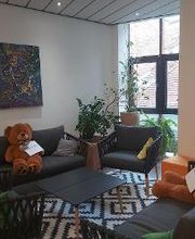 Aufenthaltsraum mit COuches, Sesseln und Tisch. auf den Couches liegen zwei Teddybären.