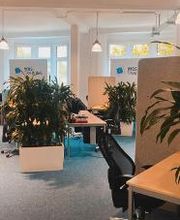 Arbeitsbereich mit mehreren Arbeitsplätzen und Grünpflanzen.