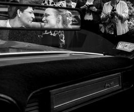 Hochzeitsfotograf Tom Maiwald - Künstlerische Schwarz-Weiß-Aufnahme eines Hochzeitspaares im Rückspiegel eines klassischen Fahrzeugs. Kreative Hochzeitsfotografie verbindet Spiegelung, Perspektive und Reportage.