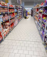 E&E Gebäudereinigung Gepflegter und hygienisch sauberer Supermarktgang mit ordentlich gefüllten Regalen und einem gereinigten, hellen Fliesenboden für ein angenehmes Einkaufserlebnis.