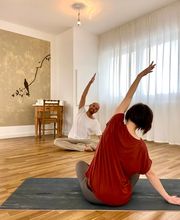 Sitzende Yogaübung mit seitlicher Dehnung in entspannter Unterrichtssituation.