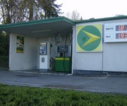 AGROLA Tankstelle in Pfäffikon, Schwyz. Grosses AGROLA Logo an Fassade, rechts daneben digitale Preisanzeige. Eine Tanksäule und ein Zahlterminal.