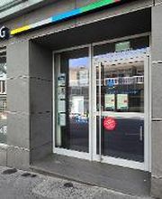 Haupteingang mit zwei großen Fenstern und Briefkasten neben der Tür. Haupteingang mit zwei großen Fenstern neben der Tür. Auf der grauen Fassade ist der Schriftzug WBS TRAINING AG angebracht.